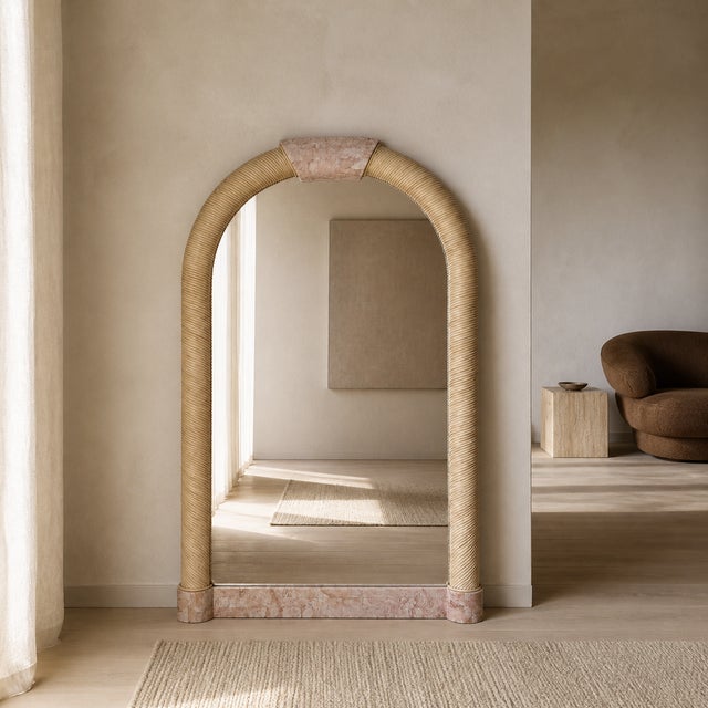 1980s Postmodern Tessellated Stone Arched Wall Mirror. A sculptural arched mirror framed in pale tessellated stone with...