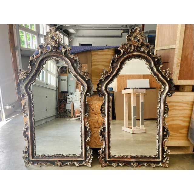 A pair of elegant giltwood wall mirrors handcrafted in Italy in the Early 20th Century. The frames have intricate, hand-...