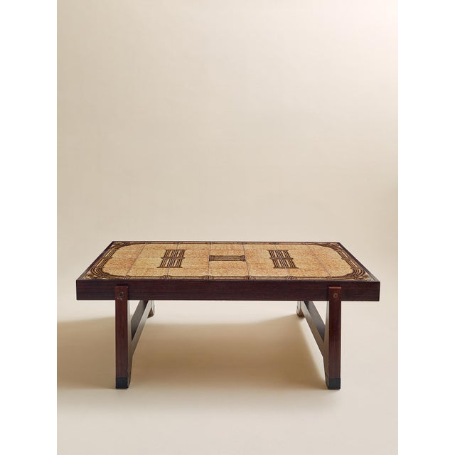 This vintage coffee table pairs a rich rosewood frame with an inset tile top in warm neutral tones. The geometric tile...