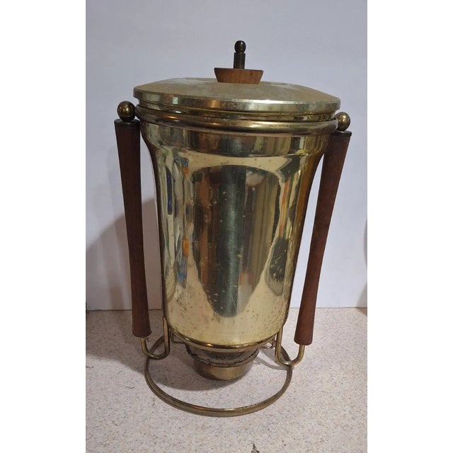 Vintage brass coffee urn dispenser with warm wood accents on the side handles, lid finial, and spigot handle....
