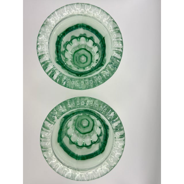 A charming pair of vintage sage green pressed glass pedestal urn vases featuring a scalloped rim, faceted base, and...