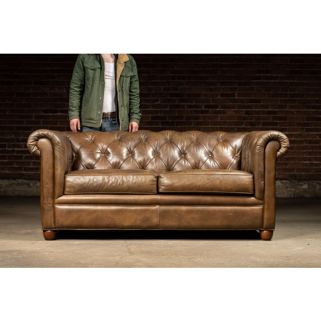 Vintage tufted leather sofa. Stylishly distressed, this piece features an all-over brown/tan gradient with a "roughened"...