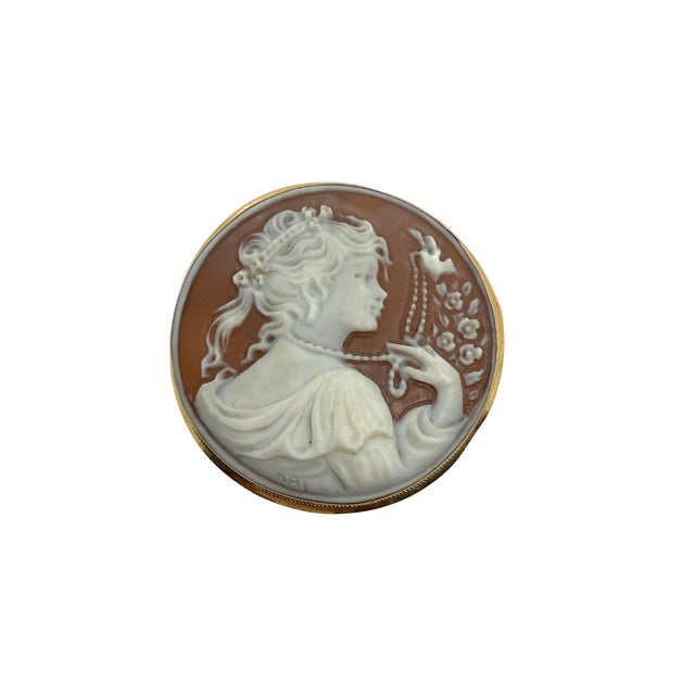 This elegant 18K gold cameo pendant, circa 1940, features a beautifully carved round shell cameo depicting a young woman...