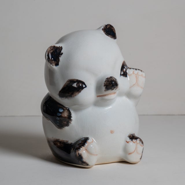 Adorable ceramic panda bear piggy bank. Sporting a yellow bow, this friendly little cub will keep your savings safe.