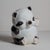 Adorable ceramic panda bear piggy bank. Sporting a yellow bow, this friendly little cub will keep your savings safe.