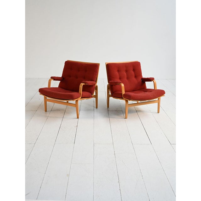 A pair of "Ingrid" armchairs designed by Bruno Mathsson for Dux in the 1960s, featuring a curved and laminated beech wood...