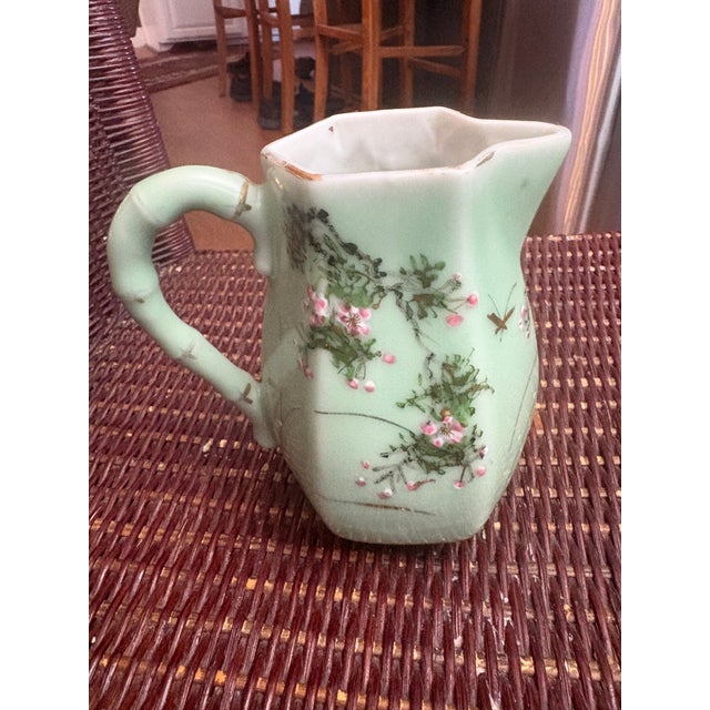 Japanese Celadon Pitcher with hand painted enamel and gold flowers. It has a bamboo style handle and is very pretty for a...