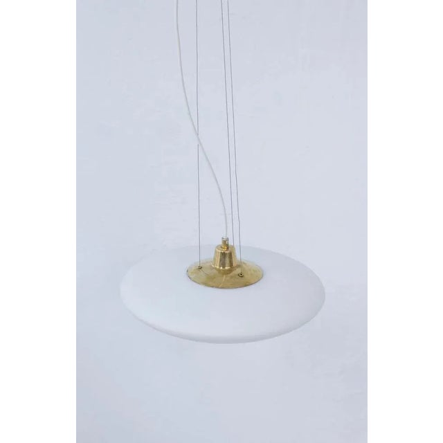 "UFO" ceiling lamp made in Sweden during the 1950s. Made with an underlay opal glass shade and brass part connected to the...