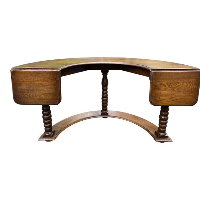A classic English hunt table in oak with a horse shoe shape and three turned legs on a semi circle base. Each end has a...