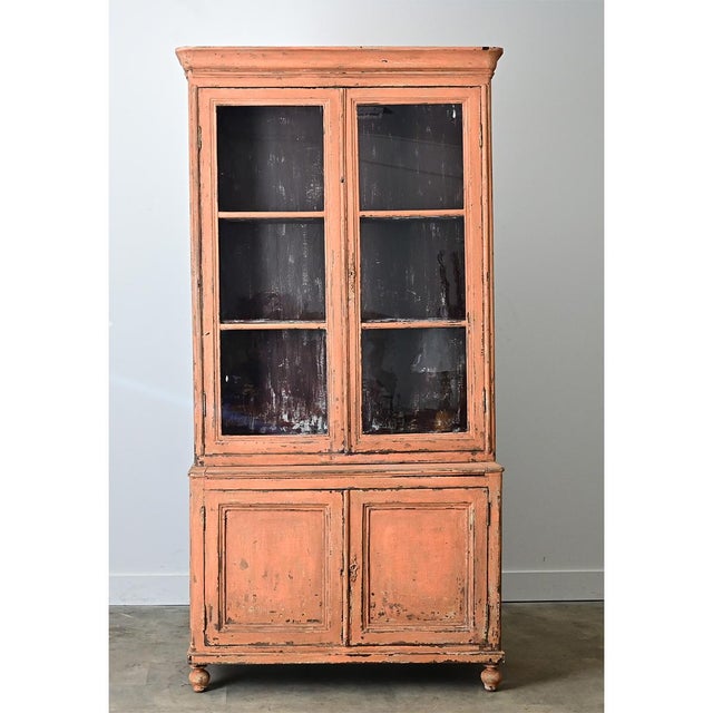 This tall French bibliotheque is perfect for a space needing storage and display. The more recently painted light orange...