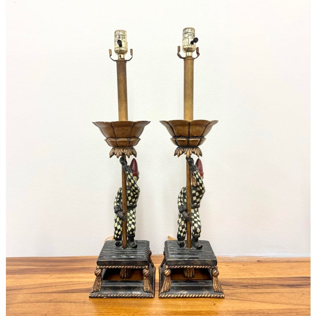 A whimsical pair of vintage table lamps featuring hand-painted jesters dressed in classic black-and-cream harlequin...