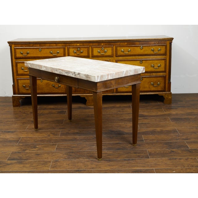 A French walnut table from the 19th century, with marble top and single drawer. Created in France during the 19th century,...