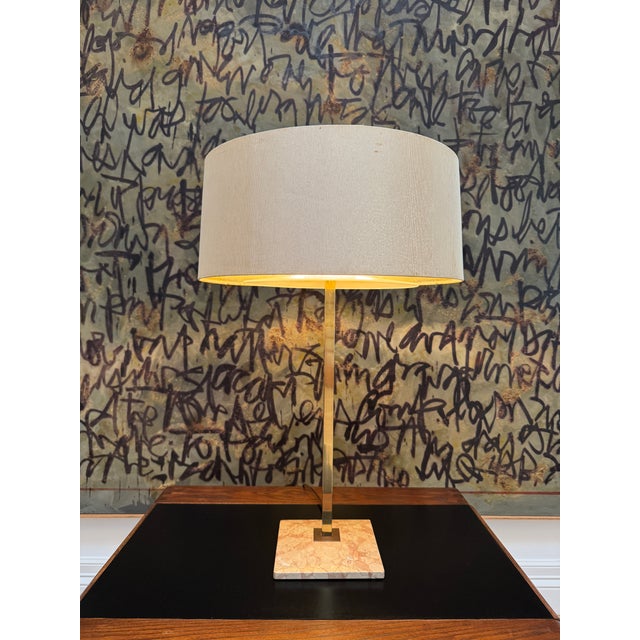 The tall stem of this mid-century American table lamp is made of polished brass and the beveled base is made of a salmon...