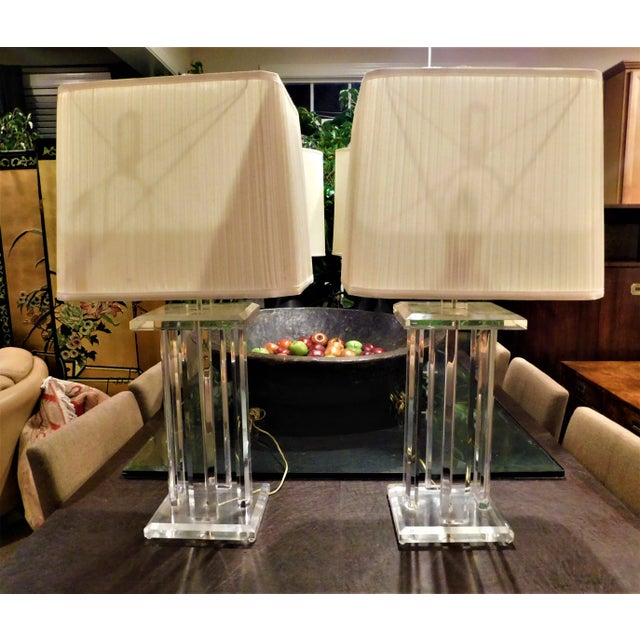 This is an awesome pair of vintage 4-column 1970's Lucite lamps, featuring original shades. There is a silver toned...