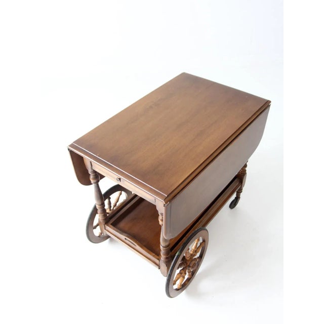This vintage Kling Colonial bar cart features a classic Early American drop-leaf form with turned legs and wagon-style...