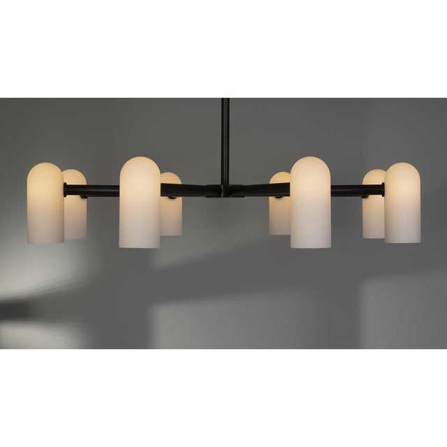 Spokes of brass hold slender lampshades, the circle of light creating a planetary effect in this striking round...