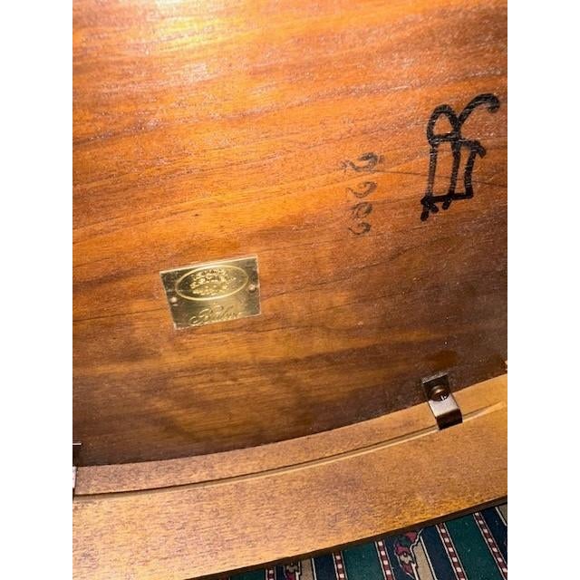 This elegant oval side table features a rich cherry wood finish with delicate inlaid floral patterns along the apron. It...
