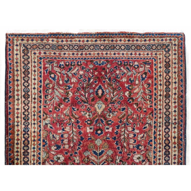 A fantastic early 20th century Persian Sarouk rug with a mirrored floral patterned field woven in pink, light and dark...