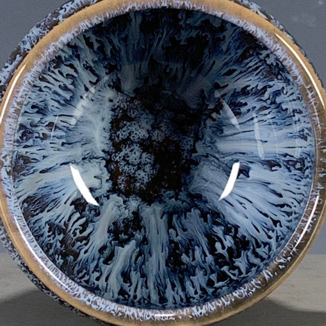 A striking Chinese ceramic tea cup (often referred to as a "master cup" for tea ceremonies). The vessel features a rounded...