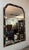 This La Barge Regency-style wall mirror pairs a deep black frame with elegant gold leaf-style accents, including sculpted...
