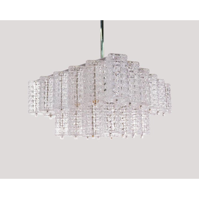Elegant chandelier with faceted rectangular glass elements on a nickel plated frame with a chromed rod and canopy....