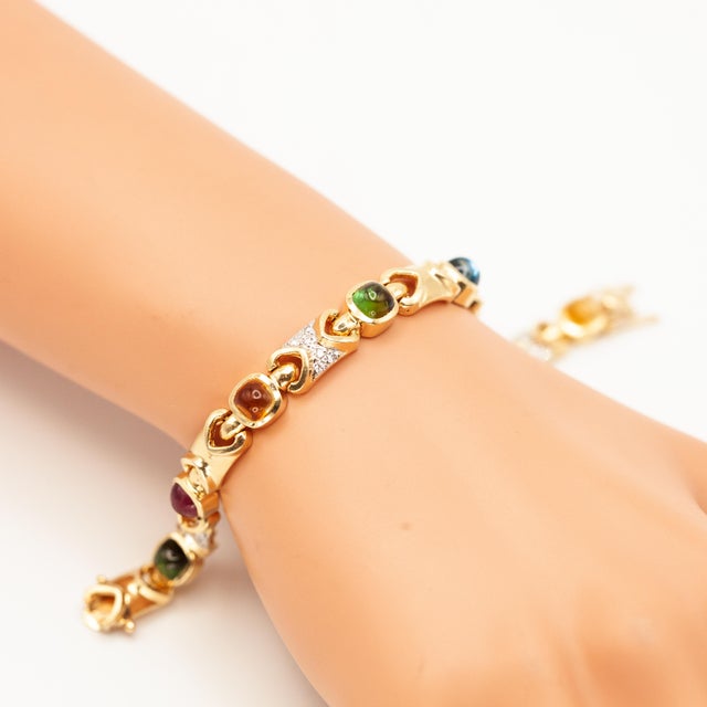 This vibrant link bracelet crafted in solid 14 karat yellow gold, showcases a colorful array of cabochon cut gemstones,...