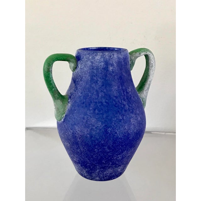 A blue and green vase in the scavo corroso technique. The applied handles and form reference its early Roman inspiration....