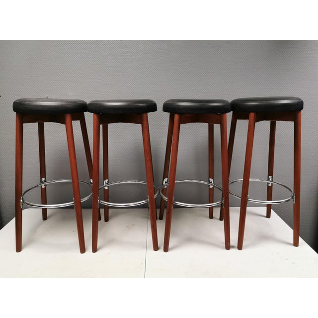 Four very attractive teak bar stools, upholstered in black imitation leather, with chrome-plated metal footrests. made by...