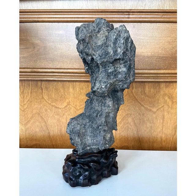 An intriguing Chinese scholar rock in vertical form presented on a custom hand-carved wood stand circa late Qing Dynasty....