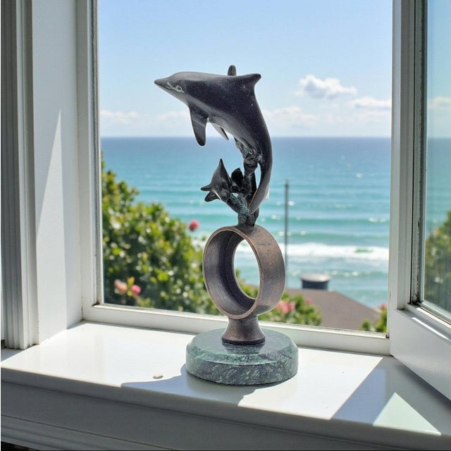 This modernist bronze sculpture depicts a pair of dolphins in an ascending composition, produced by SPI San Francisco, a...