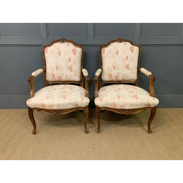 A charming pair of early 20th century French walnut armchairs, or fauteuils. Well constructed in solid walnut and...