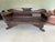 Hand-carved solid wood daybed with a dark brown finish. This piece has a slatted backrest and scrolled arms. The central...