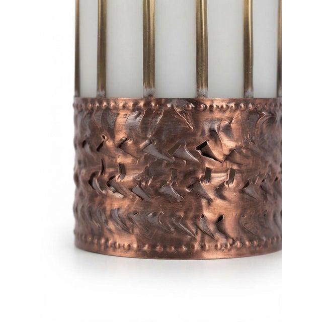 A handmade wall sconce featuring six smoky-gray fluted glass panels set within a hand-worked metal frame. Yellow brass...