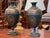 A handsome pair of tole urns in deep green with gilt decoration in the Neoclassical taste. Each urn has a classical ovoid...