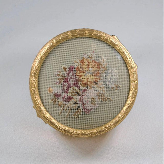 This is beautiful gilt metal box featuring a petit point floral spray under a convex glass top. A charming collector’s...