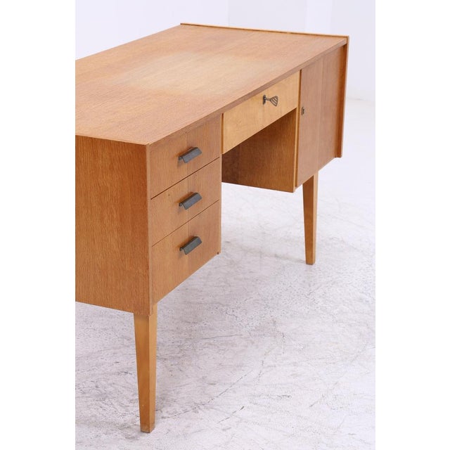 Vintage desk from the 1960s with clean lines and a practical layout. Three drawers, a lockable center drawer, and a...