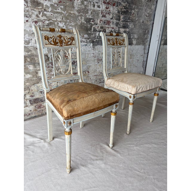 An elegant and highly decorative pair of antique neoclassical side chairs with remarkable provenance, sourced from the...