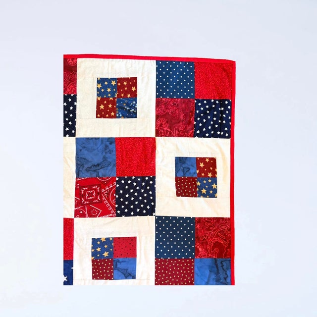 A charming handmade patchwork quilt featuring a classic four-patch block design rendered in a charming all American red,...