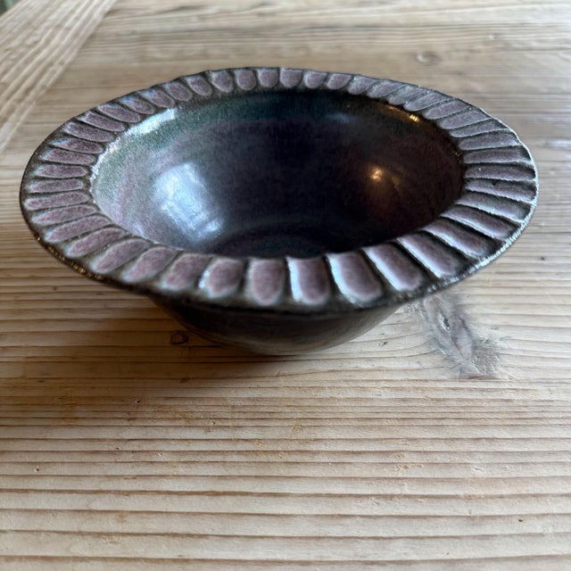 A vintage studio pottery bowl featuring a rich Tenmoku glaze with subtle oil-spot characteristics and dimensional color...