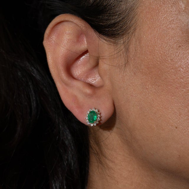 A matched pair of Zambian emeralds glows in lush green at the center of these solid 14K yellow gold sunburst stud...