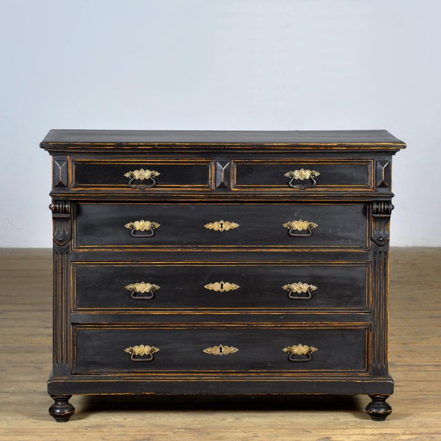 This late 19th-century chest of drawers is made of pine and oak with neoclassical influences. The black finish has a...