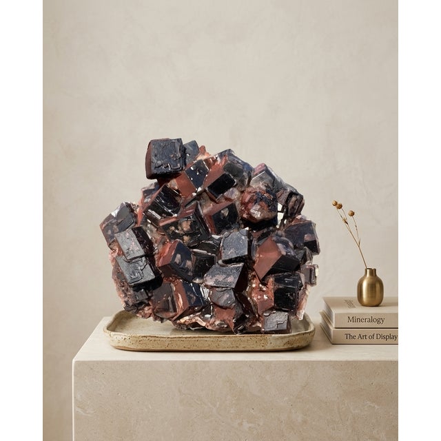 A sculptural natural Hematite-included Calcite specimen selected for its dark architectural rhombohedron formation, deep...