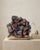 A sculptural natural Hematite-included Calcite specimen selected for its dark architectural rhombohedron formation, deep...