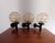 Set of three sconces with a lightly tinted pressed glass shade and a black rigid plastic mount. One of the mounts has a...