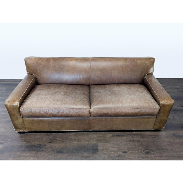This Mitchell Gold 3-seat sofa features a classic, sturdy design with brown leather upholstery. The sofa provides...