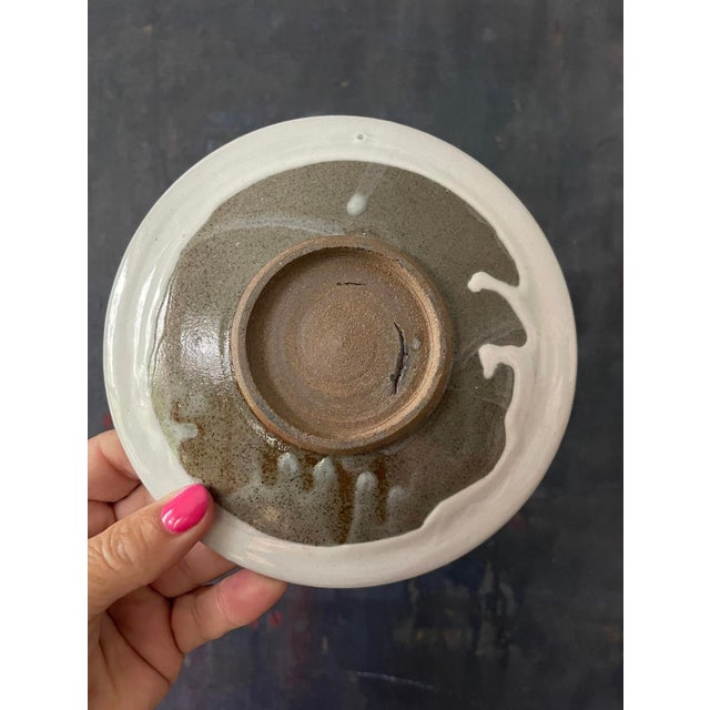 Lovely pottery plate, presented in a creamy white glaze that has a smoky deep blue swirl, slightly offset from center....