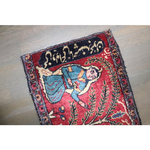 a 19th Century Persian Pictorial Small Carpet 1'4'' x 2'5'' On the left and right dark blue borders, the script is Persian...