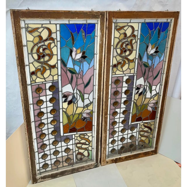 A large pair of colorful Victorian stained glass windows in walnut frames from an estate in New York. Floral patterns with...
