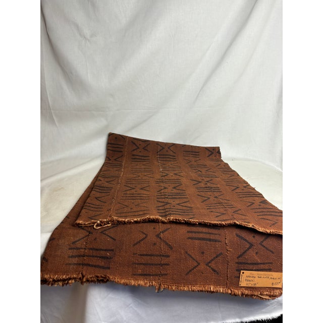 Warm, simple African Mud Cloth with natural hem. The intricately mud-dyed geometric pattern on rich brown textile is...