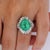 This stunning Platinum ring showcases an exquisite 6.82 carat oval-cut Colombian emerald at its center, surrounded by a...